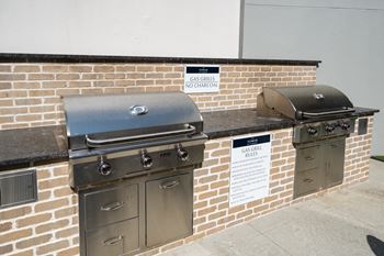 two bbq grills on the side of a brick wall